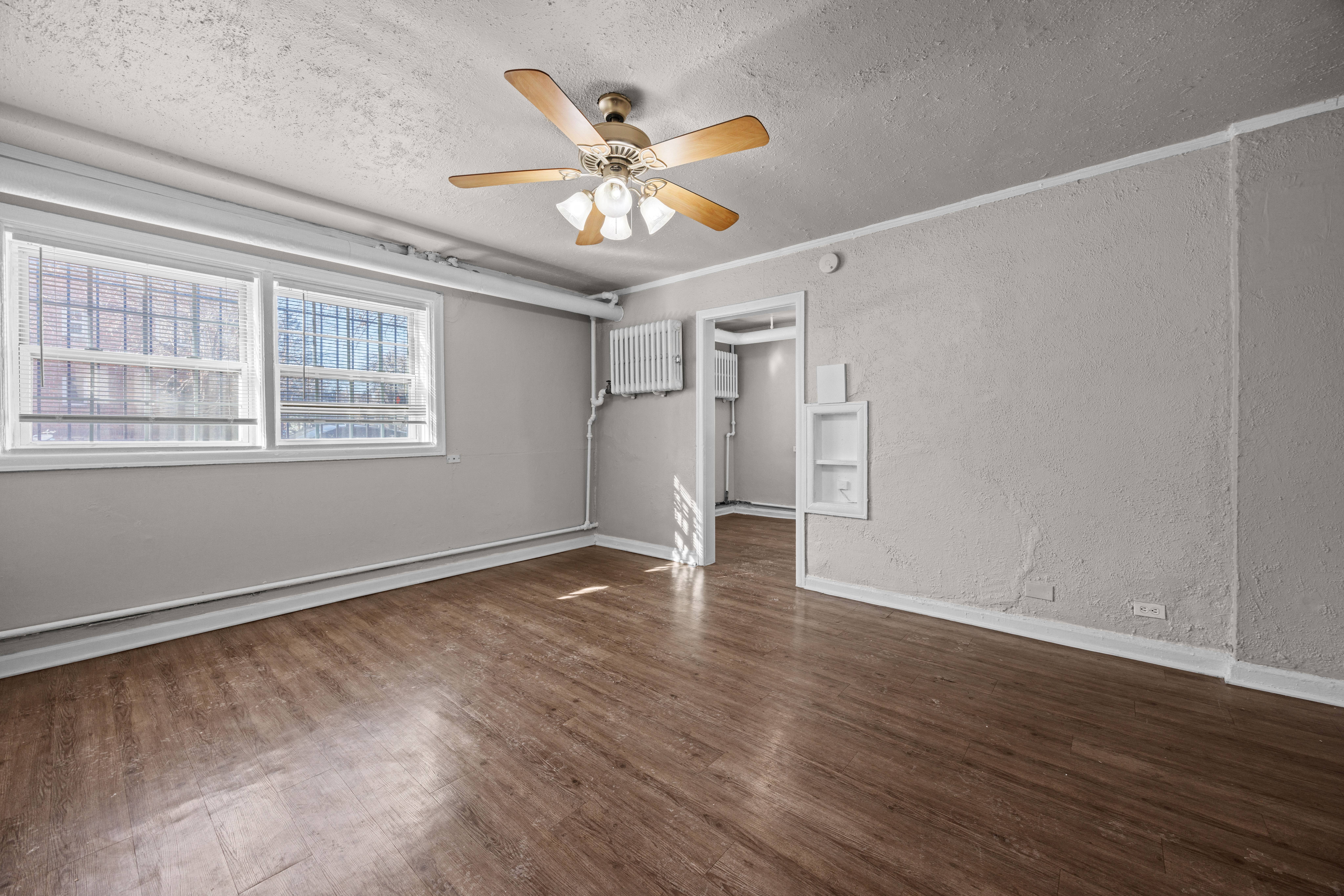 A room with a ceiling fan and wooden flooring.